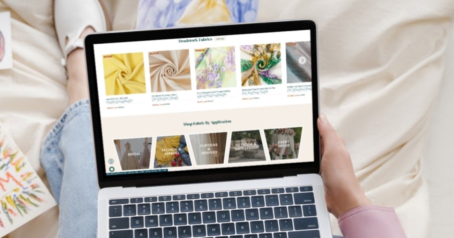 hand holding edge of laptop with fabrics on screen
