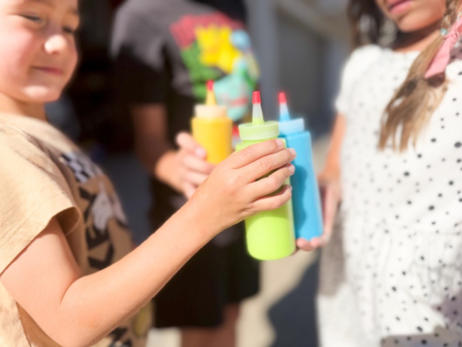 kids cheersing squirt bottles with DIY paint