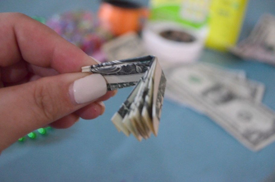 holding a folded dollar bill