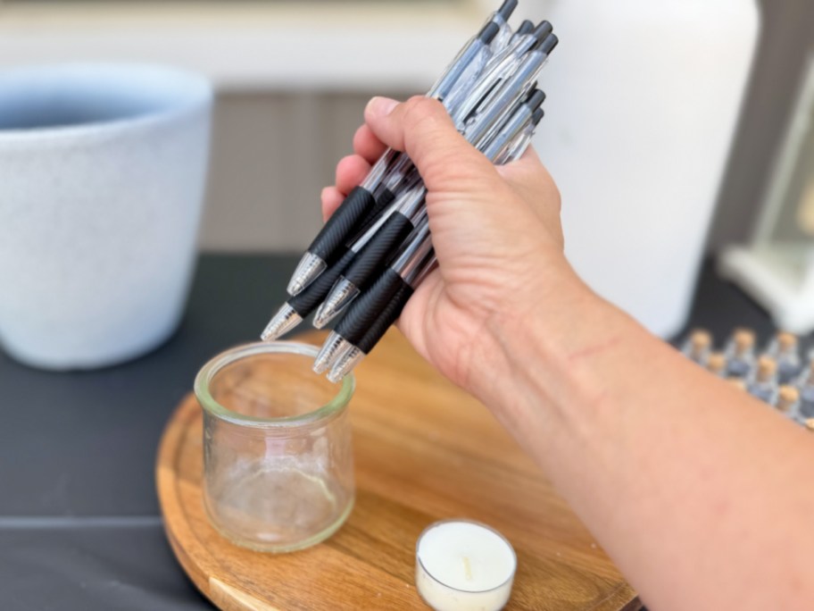 hand holding many pens putting into jar