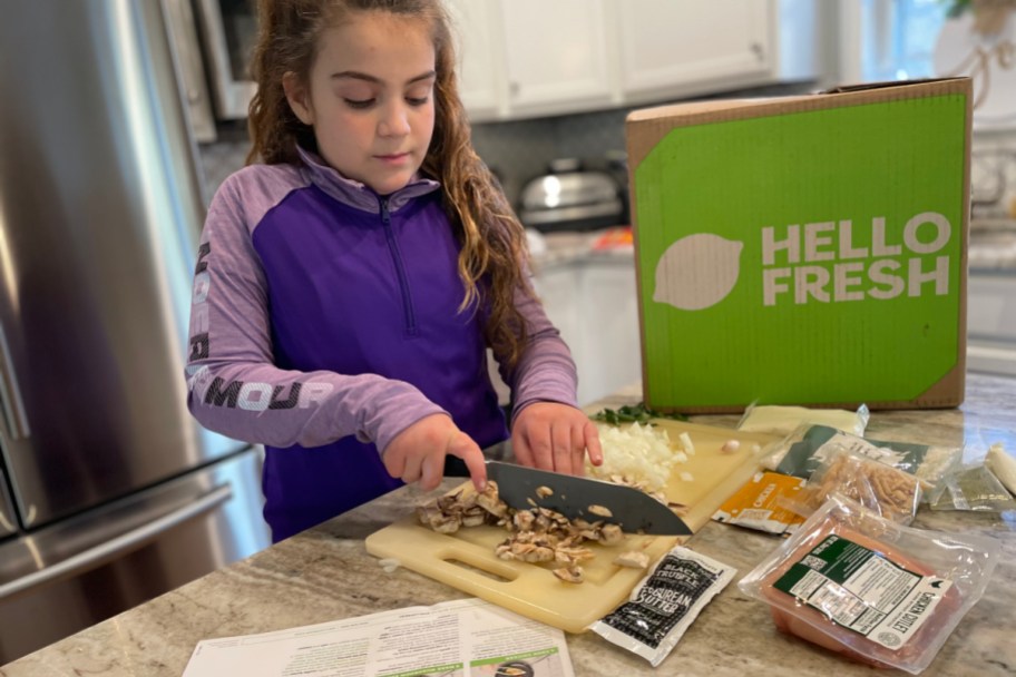 girl cutting food with hello fresh box